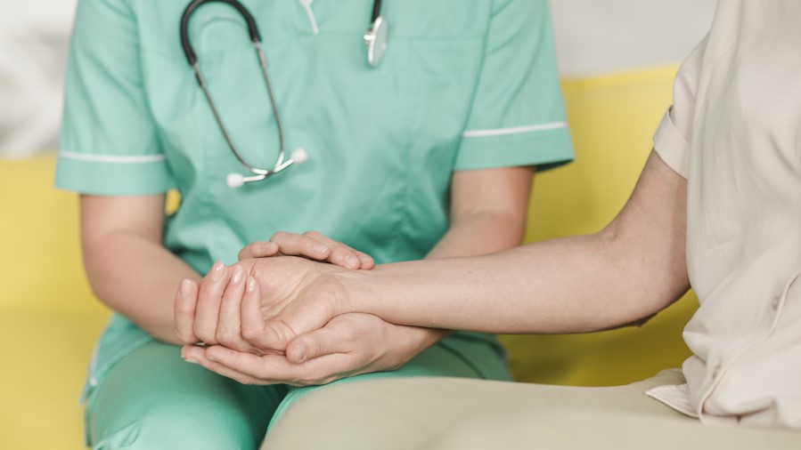 Foto de una enfermera dando la mano a un paciente.